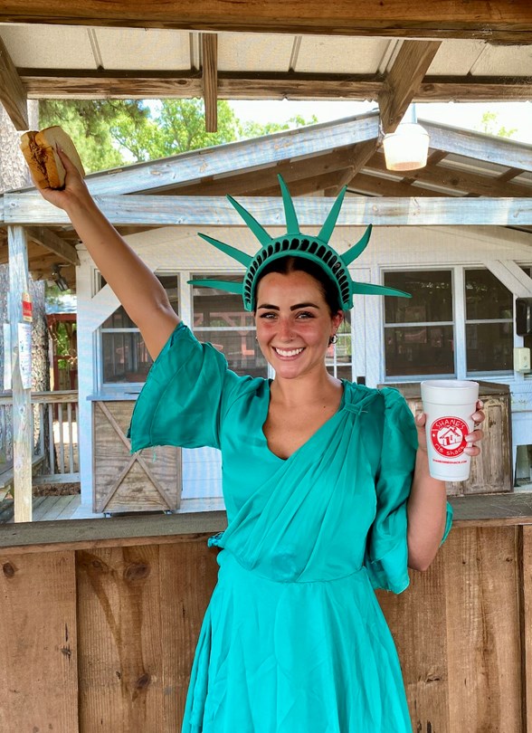 Shack Crew Member in Statue of Liberty Costume holding a big dad sandwich.